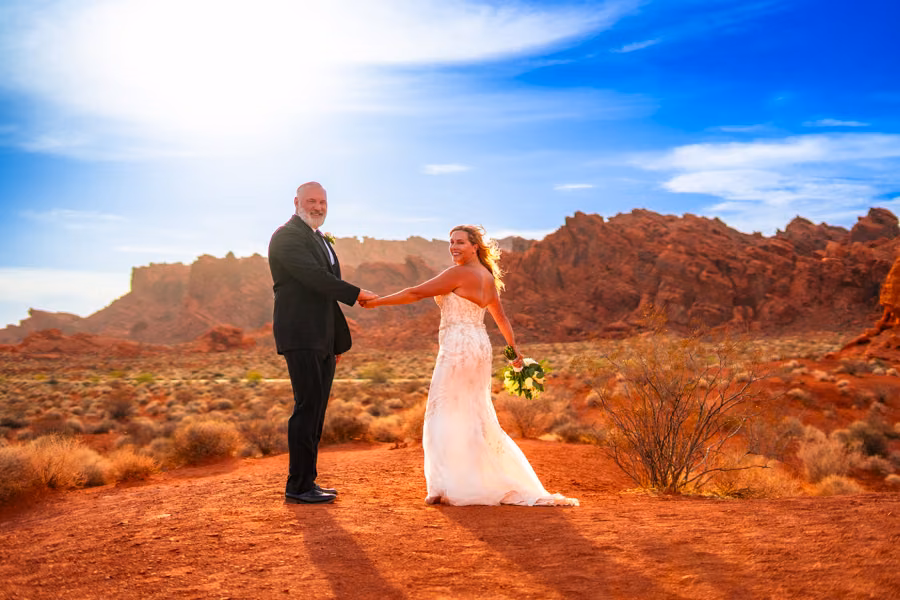 A couple walks hand in hand through the ancient crimson canyon landscape of Valley of Fire State Park, Nevada.