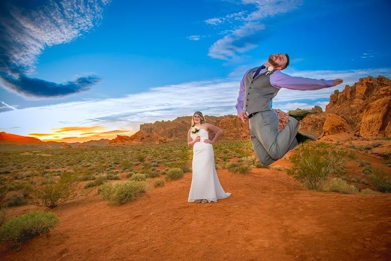 A groom leaps with joy among the dramatic red rock formations after his Valley of Fire wedding ceremony.