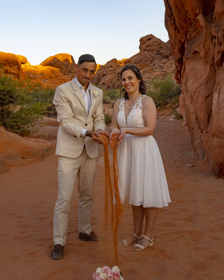 A couple performs a sand ceremony between red sandstone walls at their permitted Valley of Fire State Park wedding.